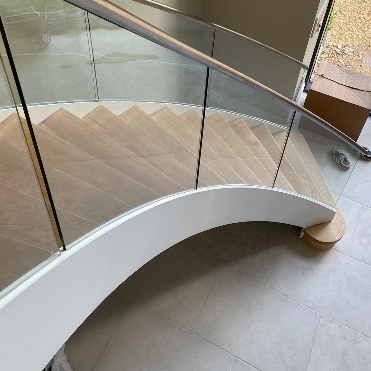 Curved stairs with white mastic applied to the outer edge on glass join where the panel meets the wood